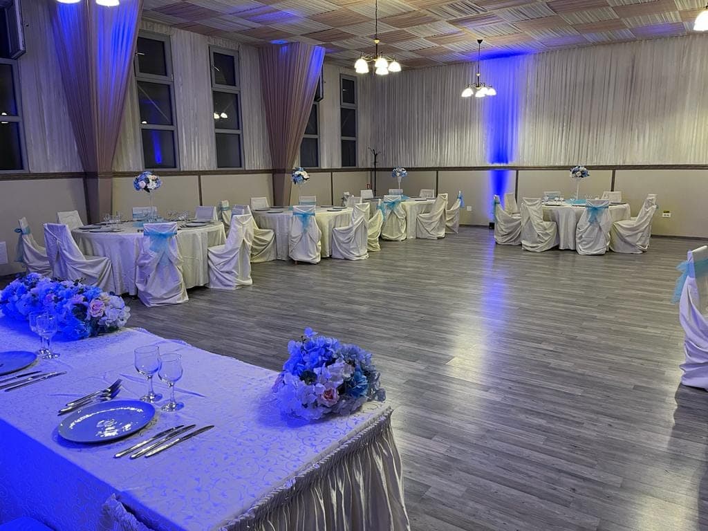 Panoramă a salonului cu draperii ivory, candelabre și uplighting albastru pe pereți
